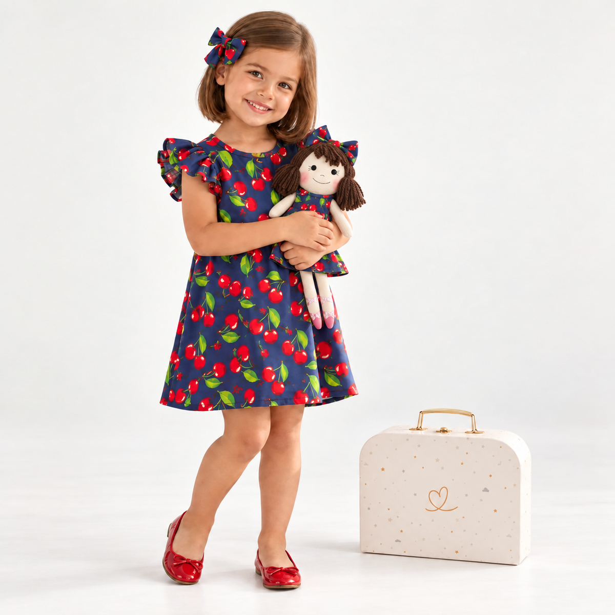 Girl in Cherry dress holding matching Alice doll, with Petit Case