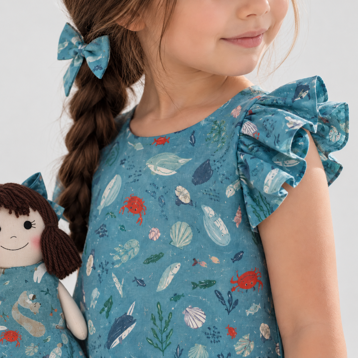Girl in Under the Sea dress holding matching Alice doll, with Petit Case