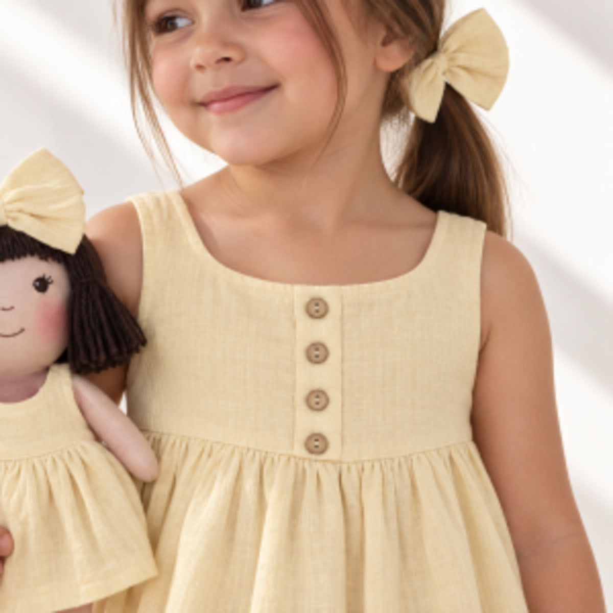 Girl in Classic Yellow dress holding matching Alice doll, with Petit Case