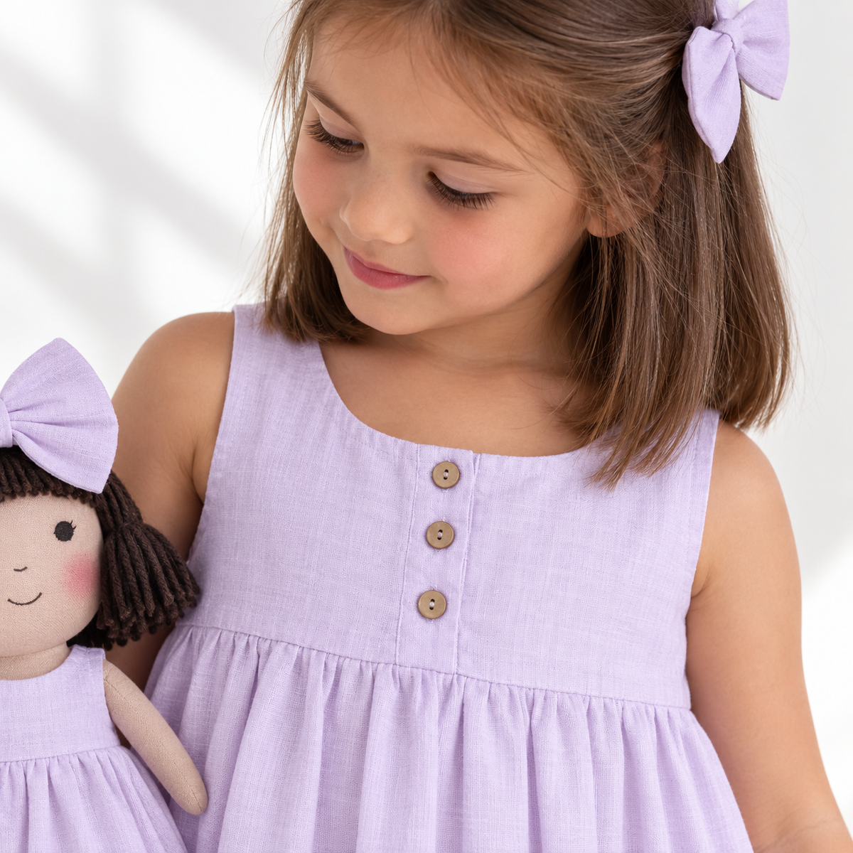 Girl in Classic Lavender dress holding matching Alice doll, with Petit Case