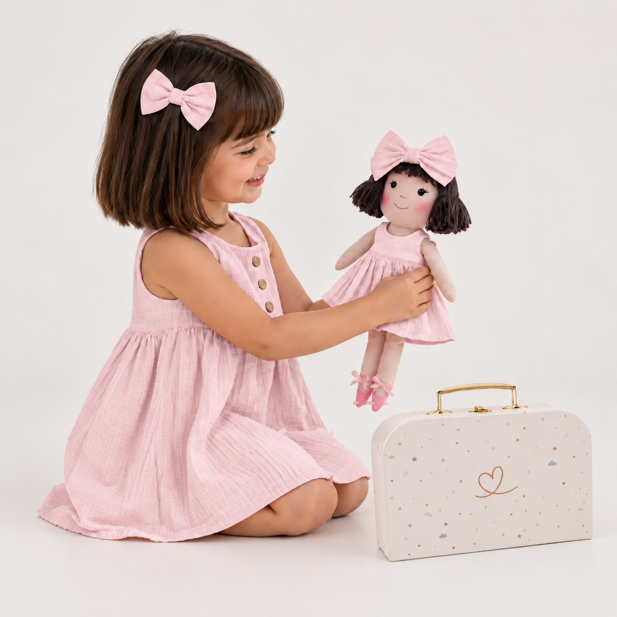Girl in Classic Pink dress holding matching Alice doll, with Petit Case