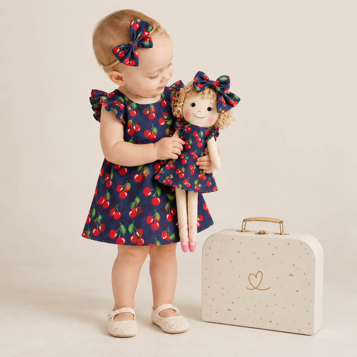 Girl in Cherry dress holding matching Annie doll, with Petit Case
