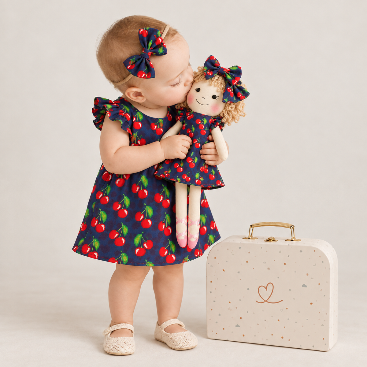 Girl in Cherry dress holding matching Annie doll, with Petit Case