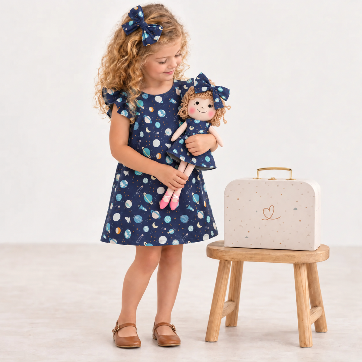 Girl in Space dress holding matching Annie doll, with Petit Case