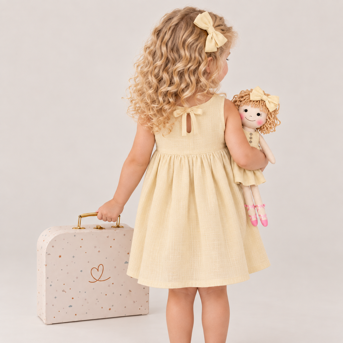 Girl in Classic Yellow dress holding matching Annie doll, with Petit Case