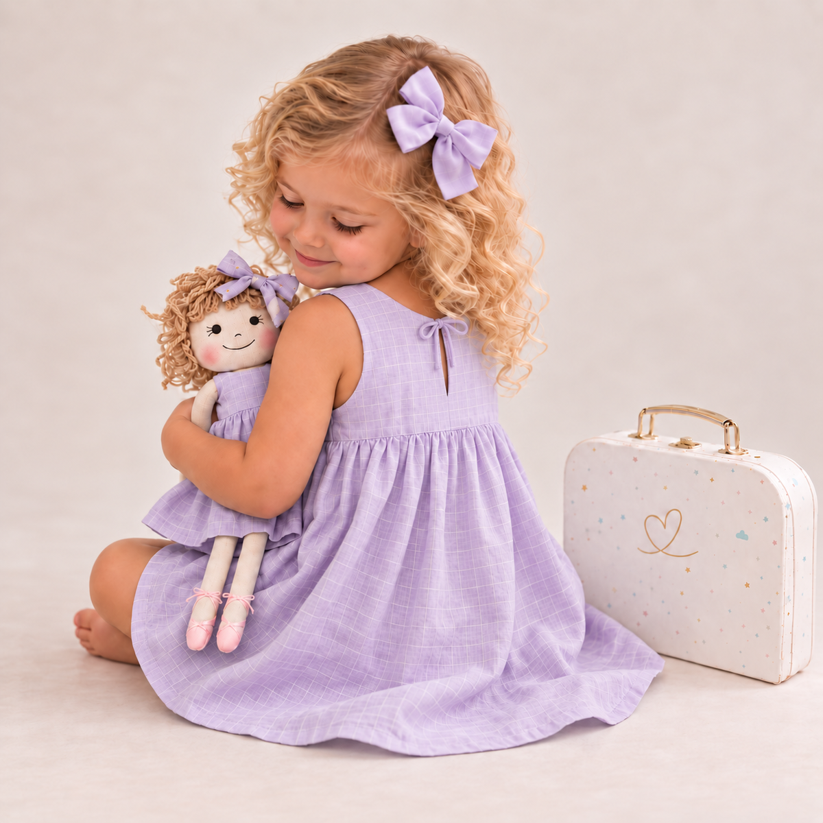 Girl in Classic Lavender dress holding matching Annie doll, with Petit Case
