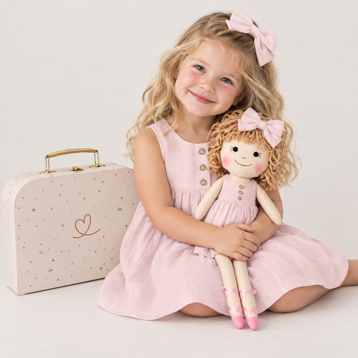 Girl in Classic Pink dress holding matching Annie doll, with Petit Case