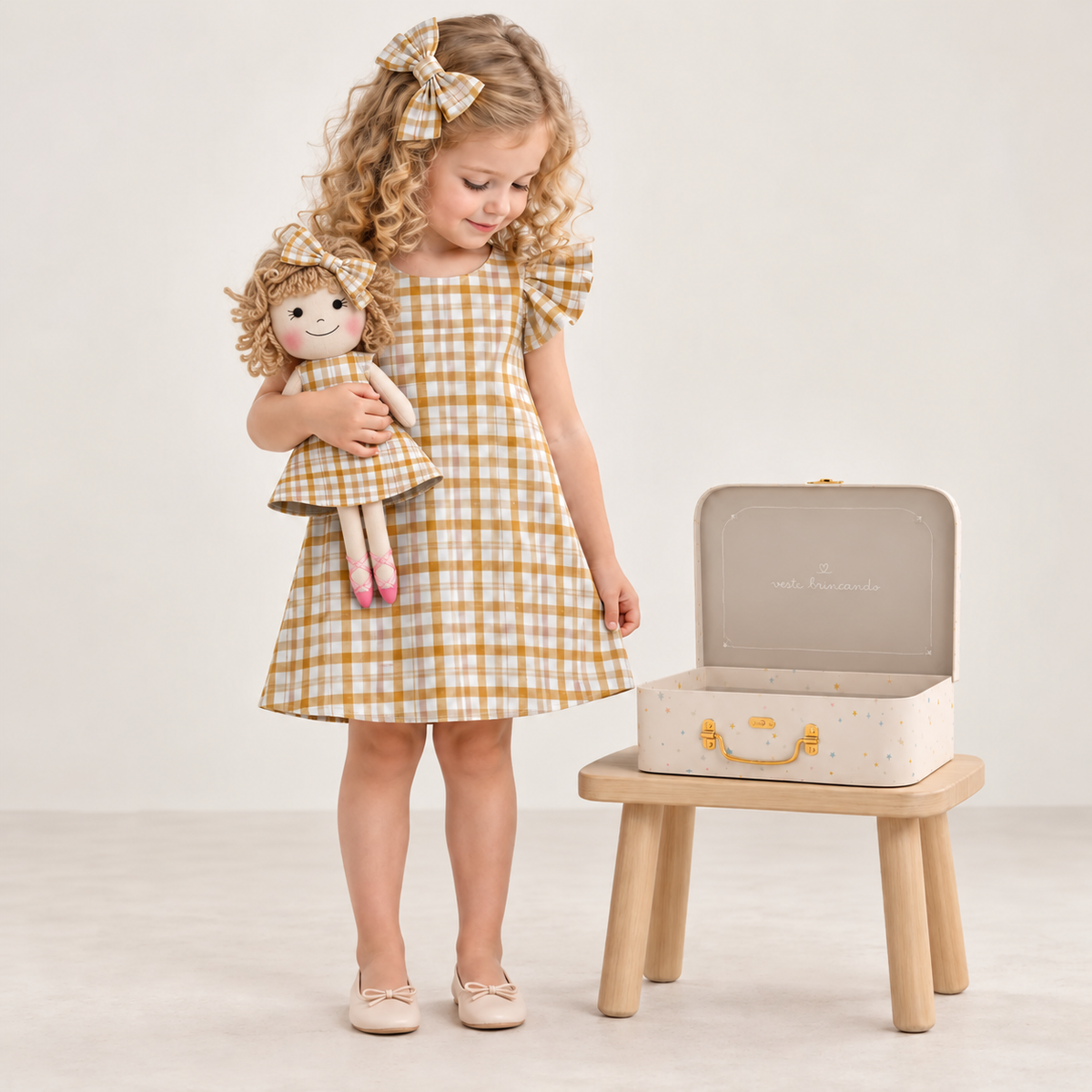 Girl in Gingham dress holding matching Annie doll, with Petit Case